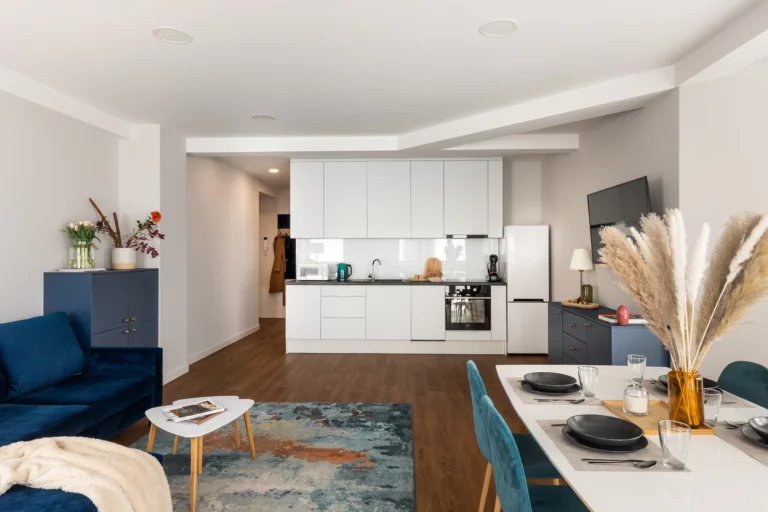 Salon z aneksem kuchennym w apartamencie na wynajem w Tychach, z granatową sofą i stołem jadalnianym