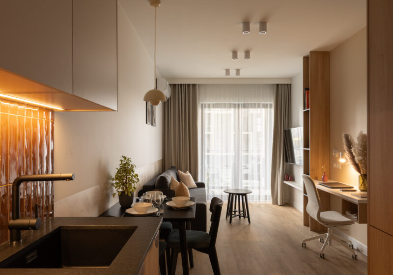 Salon z rozkładaną sofą, smart TV oraz wyjściem na balkon z widokiem na Strefę Kultury w Katowicach.