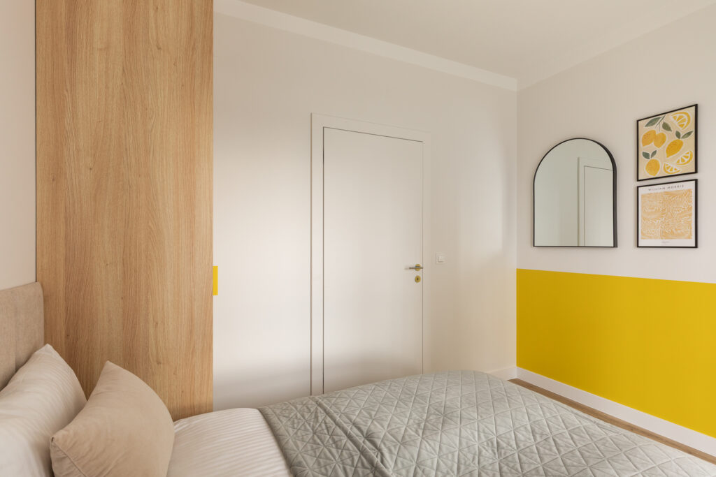 Wygodne łóżko w żółtej sypialni apartamentu typu deluxe.