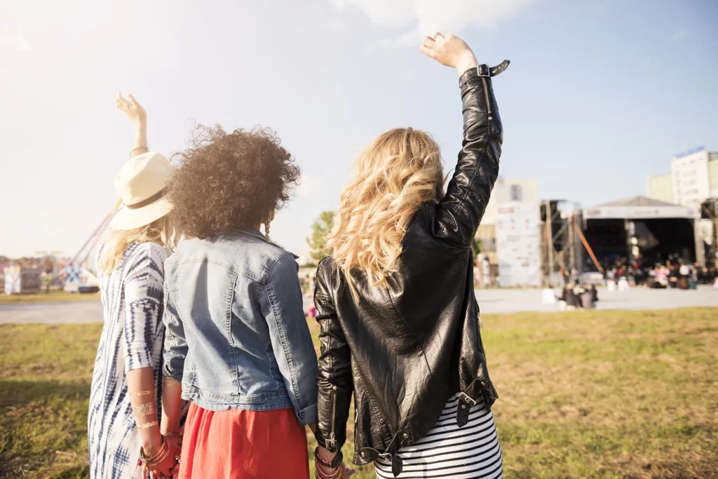 Trzy kobiety bawią się na festiwalu muzycznym w Katowicach, unosząc ręce w stronę sceny
