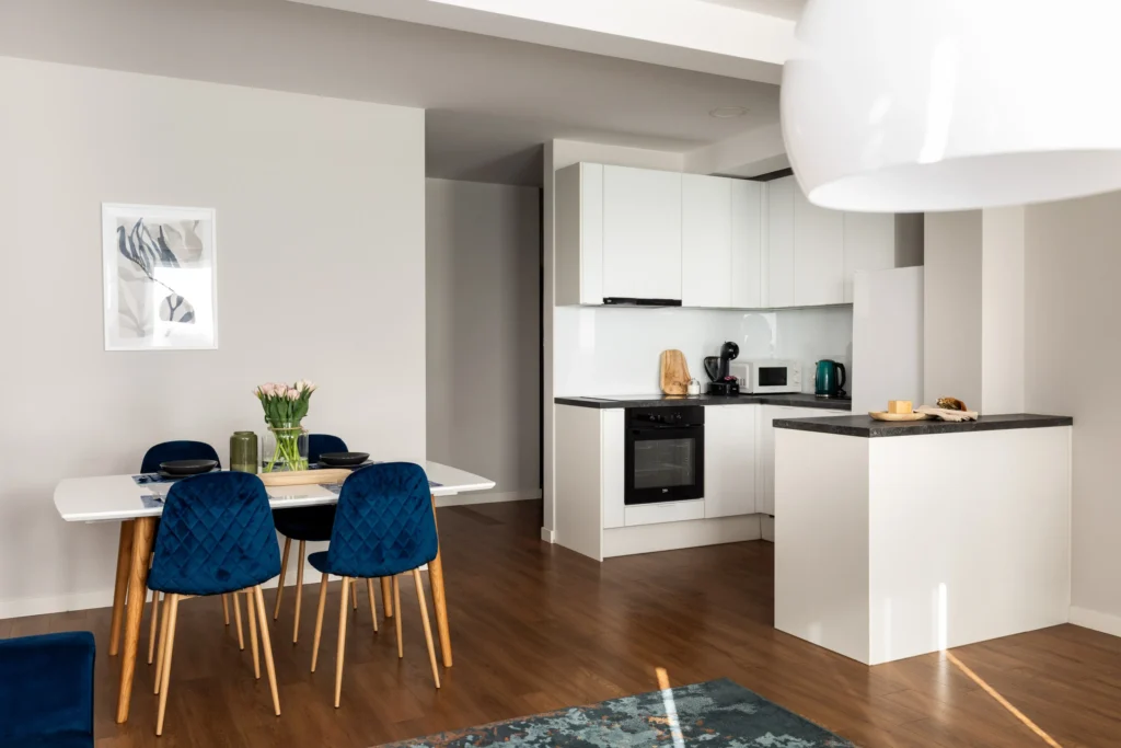 Jasna kuchnia z jadalnią i granatowymi krzesłami w apartamencie na wynajem w Tychach